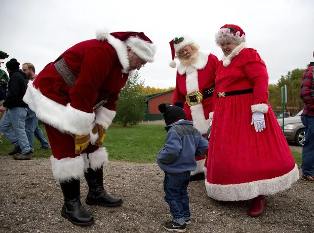 Santas and Mrs Claus greet a child at the Rooftop Landing Reindeer Farm in Clare, Michigan, U.S. October 30, 2016. (Photo by Christinne Muschi/Reuters)