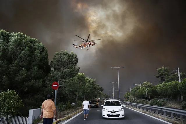 A firefighting helicopter flies over an avenue during a forest fire in Neo Voutsa, a northeast suburb of Athens, Greece, 23 July 2018. After the wildfire in Kineta a second wildfire broke out in the Penteli Mountain. Two major forest fires were raging out of control on either side of the Greek capital Monday, burning houses, prompting residents to flee and turning the sky over Athens a hazy orange from the smoke. (Photo by Alexandros Vlachos/EPA/EFE)