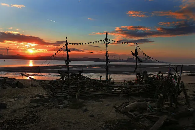 The sun rises behind a beach installation made of driftwood of the Black Pearl pirate ship on New Brighton beach, Liverpool, northwest England, Thursday, October 15, 2015. The installation was created by artist Frank Lund and Major Mace. (Photo by Peter Byrne/PA Wire via AP Photo)