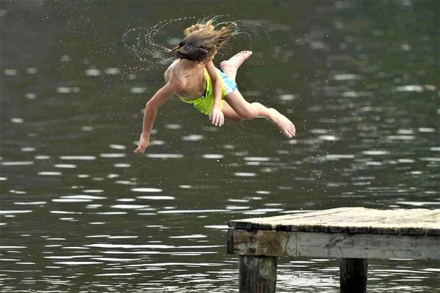 Hunter Newsom makes a spinning dive into the Ross Barnett Reservoir at Bobby Cleveland Park at Lakeshore in Rankin County, Miss., as residents seek ways to beat the heat, Friday, June 30, 2023. Hot weather and powerful storms are bringing about dangerous and uncomfortable conditions to parts of the U.S. heading into a long July Fourth weekend. (Photo by Rogelio V. Solis/AP Photo)