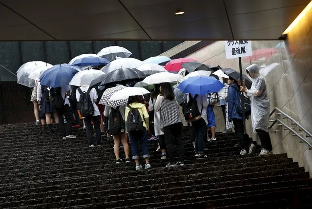 People holding umbrellas wait in a queue to buy goods in Tokyo, Japan September 8, 2015. (Photo by Issei Kato/Reuters)