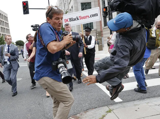 Attorney Kevin Downing, center, with the defense team for Paul Manafort, watches as television cameraman Chris Plater, trips and falls backwards outside of federal court in Washington, Friday, September 14, 2018. Former Trump campaign chairman Paul Manafort has pleaded guilty to two federal charges as part of a cooperation deal with prosecutors. The deal requires him to cooperate “fully and truthfully” with special counsel Robert Mueller's Russia investigation. The charges against Manafort are related to his Ukrainian consulting work, not Russian interference in the 2016 presidential election. (Photo by Pablo Martinez Monsivais/AP Photo)