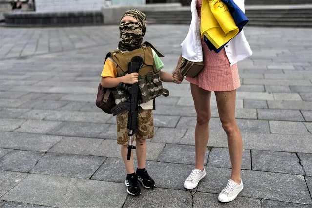 Dressed as a soldier, Artem Mihaylenko, 7, visits the Independence Square with his mother in Kyiv, Ukraine, Sunday, July 9, 2023. Life in the capital of a war-torn country seems normal on the surface. In the mornings, people rush to their work holding cups of coffee. Streets are filled with cars, and in the evenings restaurants are packed. But the details tell another story. (Photo by Jae C. Hong/AP Photo)