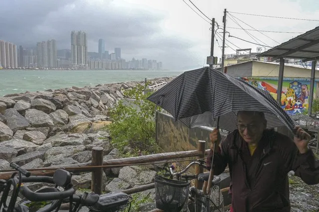 A man covers himself with umbrella as he walks by a coastal area after Typhoon Saola struck the city with strong winds and rain, in Hong Kong, Saturday, September 2, 2023. The typhoon made landfall in southern China before dawn Saturday after nearly 900,000 people were moved to safety and most of Hong Kong and other parts of coastal southern China suspended business, transport and classes. (Photo by Billy H.C. Kwok/AP Photo)