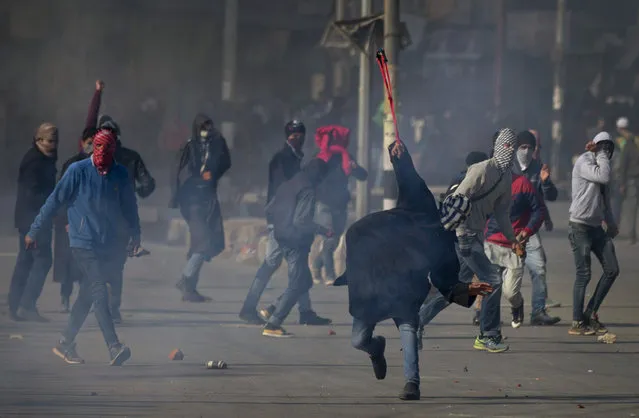 A Kashmiri Muslim protester uses a sling to throw stones at Indian policemen during a protest in Srinagar, Indian-controlled Kashmir, Friday, January 22, 2016. Police in the main city of Indian-controlled Kashmir Friday fired tear gas and rubber bullets to disperse Kashmiri protesters, demonstrating against the killing of a young man two days ago during an ant-India protest in a southern Kashmiri village, reports said. (Photo by Dar Yasin/AP Photo)