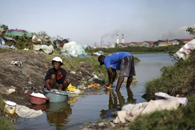 People wash clothes in a pond close to Cite Soleil, in Port-au-Prince, March 21, 2015. (Photo by Andres Martinez Casares/Reuters)
