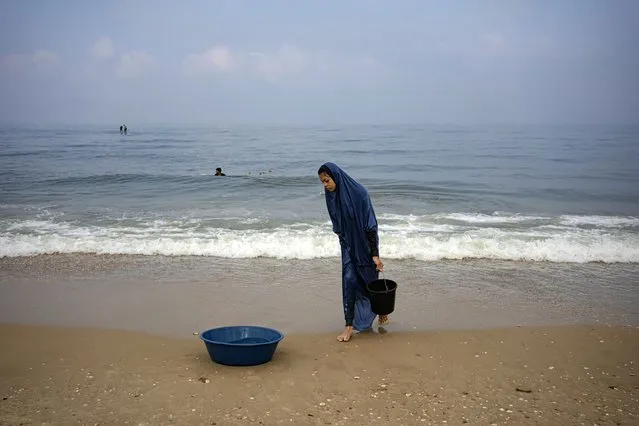 Palestinian woman collects seawater to wash clothes at the beach in Deir al Balah, Gaza Strip, on Thursday, November 2, 2023. (Phoot by Fatima Shbair/AP Photo)