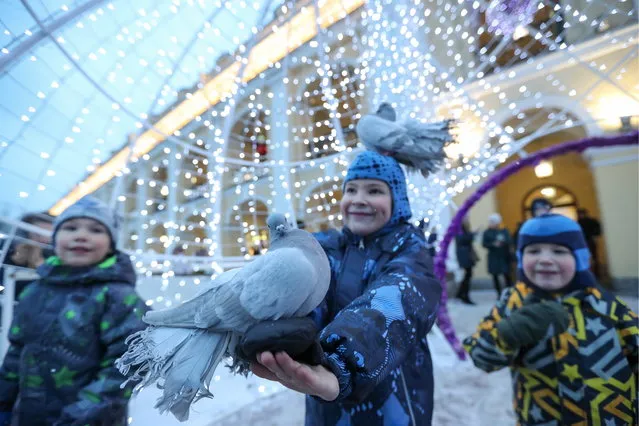 Children holding pigeons by St Petersburg's Gostiny Dvor on December 20, 2018. (Photo by Alexander Demianchuk/TASS via Getty Images)