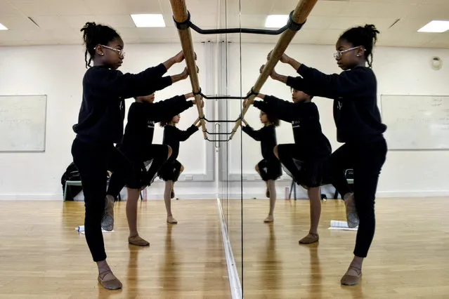 Kioni, 10, Keturah, 8, and Maya, 10, practice ballet at the barre during their class at Pointe Black Ballet School in south London, Britain on January 21, 2023. (Photo by Alishia Abodunde/Reuters)