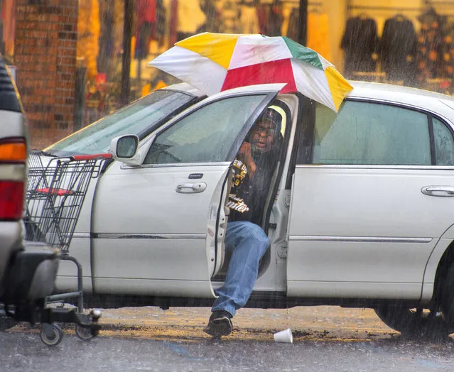 Harry Anderson tries to stay relatively dry as he maneuvers his umbrella into position before slipping out of his car during a steady rainstorm, Thursday, December 27, 2018, in Baton Rouge, La. He was preparing to go inside Shoppers Value on Plank Road near J.H. Cooney Street to buy some groceries, and he succeeded in staying dry, for the most part, he said. (Photo by Travis Spradling/The Advocate via AP Photo)