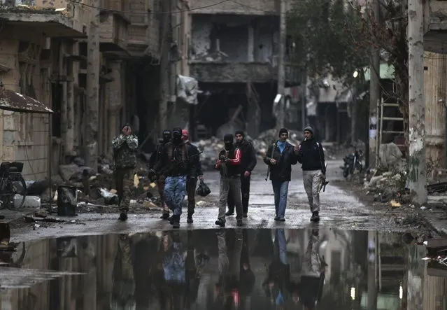“Free Syrian Army” fighters walk along a damaged street filled with debris in Deir al-Zor, eastern Syria December 5, 2013. (Photo by Khalil Ashawi/Reuters)