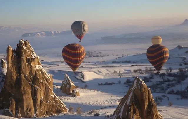 Hot-air balloons glide above snow covered fairy chimneys in the historical Cappadocia region, located in Central Anatolia's Nevsehir province, Turkey on January 18, 2019. (Photo by Behcet Alkan/Anadolu Agency/Getty Images)