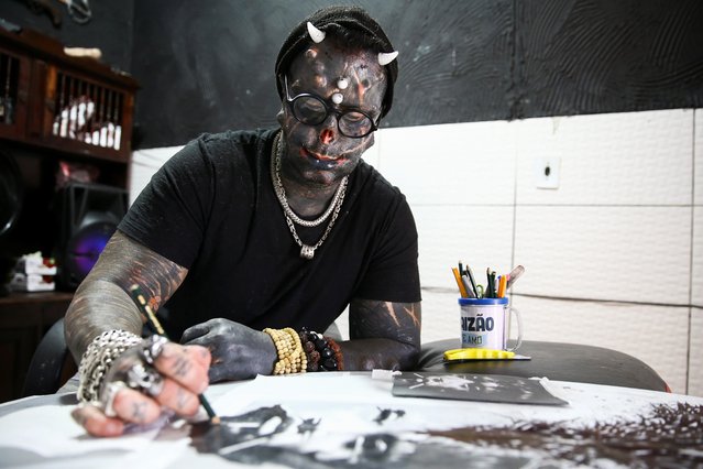 Brazilian tattoo artist and body modifier Michel Praddo, also known as Diabao or Human Satan, draws in his studio in Praia Grande, Brazil on August 18, 2021. Even though he has faced prejudice and hate, Prado has learned not to care what others think about him. “What I desire differs from society's established patterns”, he said. “I receive so much love, so much love that it (prejudice) has become so small”. (Photo by Carla Carniel/Reuters)