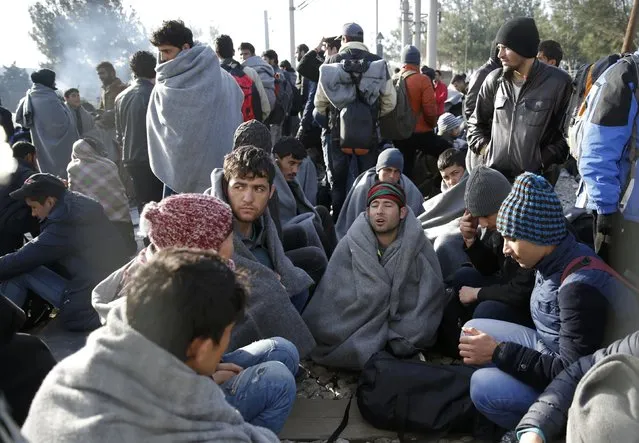Migrants rest next to a border fence at the Greek-Macedonian border, after additional passage restrictions imposed by Macedonian authorities left hundreds of them stranded near the village of Idomeni, Greece, February 23, 2016. The picture was taken from the Macedonian side of the border. (Photo by Marko Djurica/Reuters)