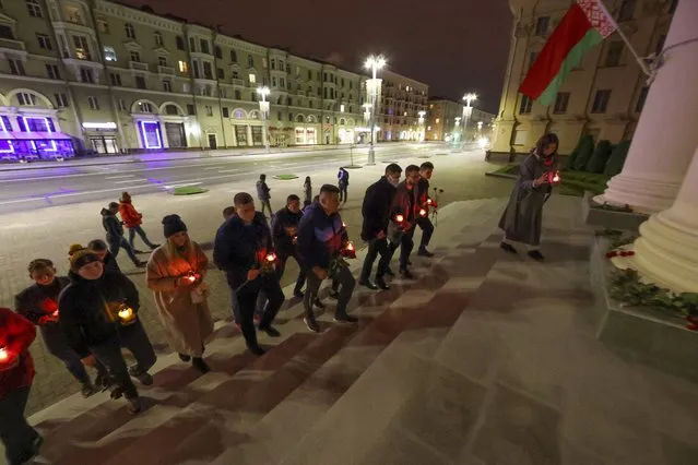 People carry candles to the Belarusian state security service, KGB headquarters in the center of Minsk, Belarus, Tuesday, September 28, 2021. The Belarusian Ministry of Information blocked access to the Komsomolskaya Pravda in Belarus website, the Belarusian subsidiary of a popular Russian newspaper of the same name. The access to it was restricted several hours after it ran a story about an alleged shootout in an apartment in Minsk, the capital of Belarus, during which two people, an opposition supporter and a KGB officer were killed. (Photo by Maxim Guchek/BelTA Pool Photo via AP Photo)