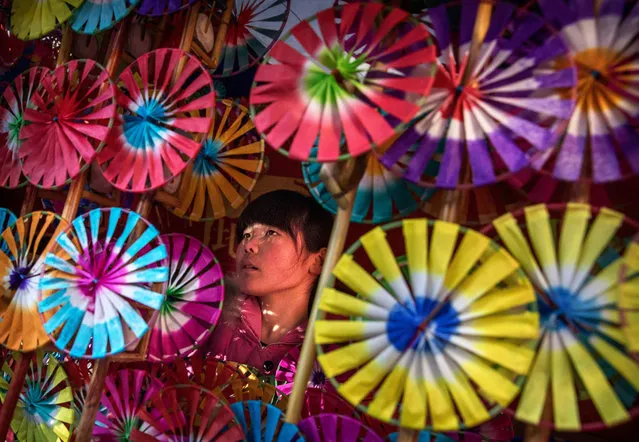 A Chinese woman sells traditional handheld windmills at a local temple fair on the fifth day of the Chinese Lunar New Year on February 1, 2017 in Beijing, China. China is marking the year of the Fire Rooster. (Photo by Kevin Frayer/Getty Images)