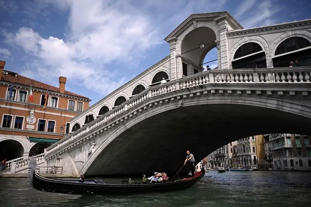 Tourists go for a gondola ride by the 16th-century stone arch Rialto Bridge at the Grand Canal in Venice on September 7, 2021, within a ceremony after the bridge underwent major restoration. (Photo by Marco Bertorello/AFP Photo)