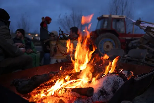 French farmers, standing around a fire, picket as they block truck access to the SOCAMIL, the purchasing center for Leclerc, as part of their protest over price pressures, taxes and green regulation, grievances shared by farmers across Europe, in Castelnaudary, south of France, on January 24, 2024. (Photo by Nacho Doce/Reuters)