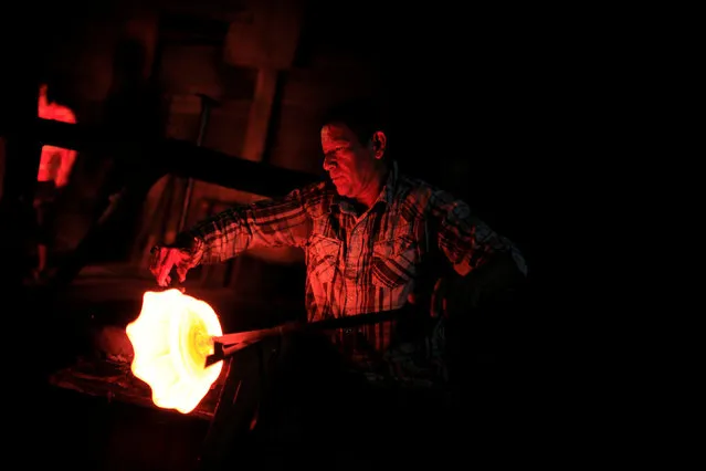 A glassmaker forms molten glass next to a furnace at Cespedes factory in Olocuilta, El Salvador February 8, 2017. (Photo by Jose Cabezas/Reuters)