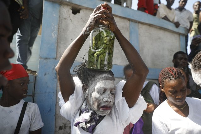 A person believed to be possessed by a Gede spirit attends a ceremony honoring the Vodou spirit of Baron Samedi and Gede at the National Cemetery in Port-au-Prince, Haiti, Monday. November 1, 2021. Followers of Vodou are marking the Fete Gede celebration of the spirits, equivalent to the Roman Catholic festivity of the Day of the Dead and All Saints Day. (Photo by Joseph Odelyn/AP Photo)