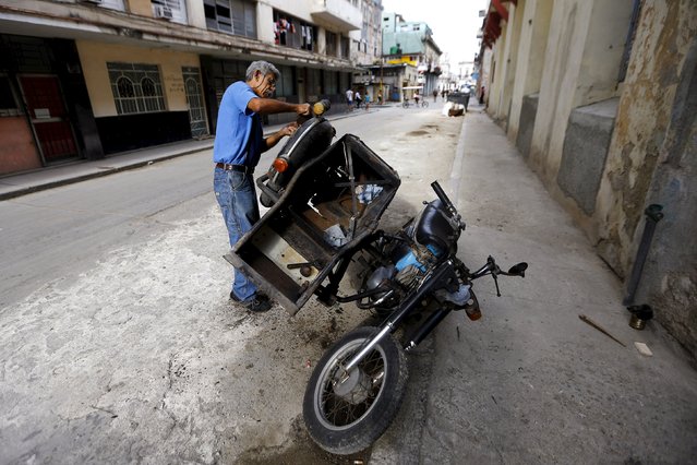 A man repairs a motorcycle with a sidecar on a street in Havana, Cuba, March 19, 2016. (Photo by Ivan Alvarado/Reuters)