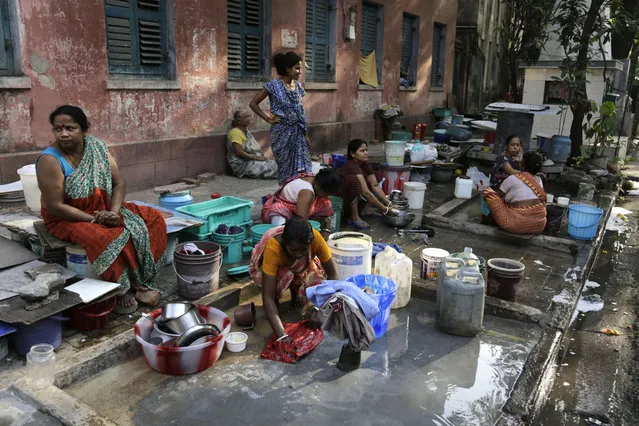 Residents of an area gather around a roadside water source to wash their clothes and fill drinking water for their houses in Kolkata, India, Tuesday, March 22, 2016. (Photo by Bikas Das/AP Photo)