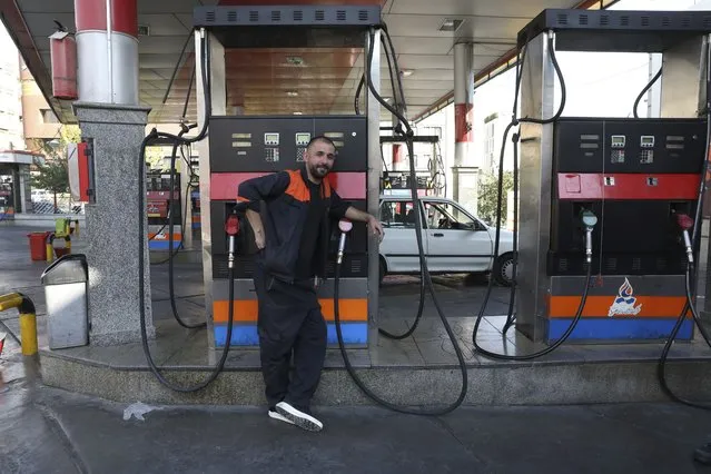 A worker leans against a gasoline pump that has been turned off, at a gas station in Tehran, Iran, Tuesday, October 26, 2021. Gas stations across Iran on Tuesday suffered through a widespread outage of a system that allows consumers to buy fuel with a government-issued card, stopping sales. One semiofficial news agency referred to the incident as a cyberattack. (Photo by Vahid Salemi/AP Photo)