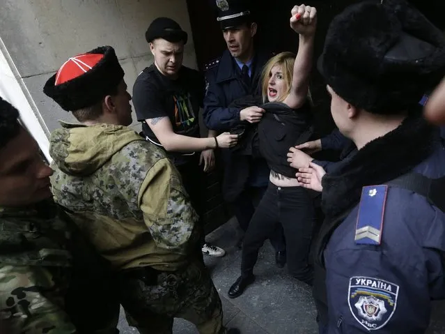 Femen released a statement on their website saying their members had been “severely beaten” by “pro-Russian activists” and arrested. Video footage has also emerged showing the women being carried away by security guards before being put into a police van. (Photo by Maxim Shipenkov/EPA)