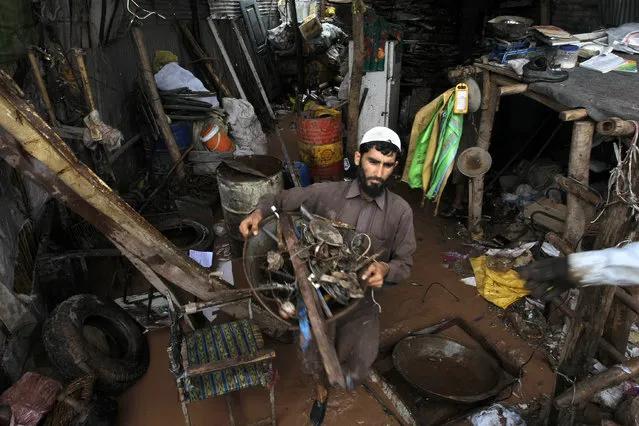A Pakistani villager salvages his belongings from his flooded house on the outskirts of Peshawar, Pakistan, Sunday, April 3, 2016. (Photo by Mohammad Sajjad/AP Photo)