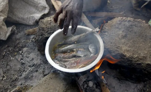 A Burundian refugee cooks a meal on the shores of Lake Tanganyika in Kagunga village in Kigoma region in western Tanzania, as they wait for MV Liemba to transport them to Kigoma township, May 18, 2015. (Photo by Thomas Mukoya/Reuters)