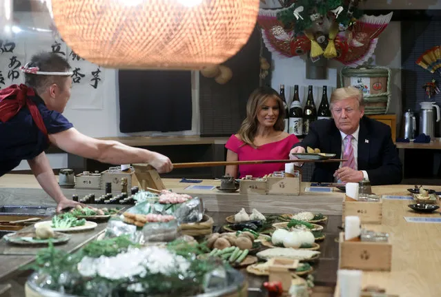 U.S. President Donald Trump, with first lady Melania Trump, receives a plate of food from a chef as they and Japanese Prime Minister Shinzo Abe and his wife Akie Abe have a couples dinner in Tokyo, Japan May 26, 2019. (Photo by Jonathan Ernst/Reuters)