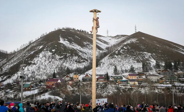A man climbs up a wooden pole to get a prize during celebration of Maslenitsa, or Pancake Week, a pagan holiday marking the end of winter, at the Bobrovy Log ski resort in the suburbs of the Siberian city of Krasnoyarsk, Russia, February 26, 2017. (Photo by Ilya Naymushin/Reuters)