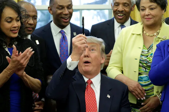 U.S. President Donald Trump holds up a pen after signing the HBCU executive order in the Oval Office of the White House, in Washington, DC, U.S. February 28, 2017. (Photo by Yuri Gripas/Reuters)