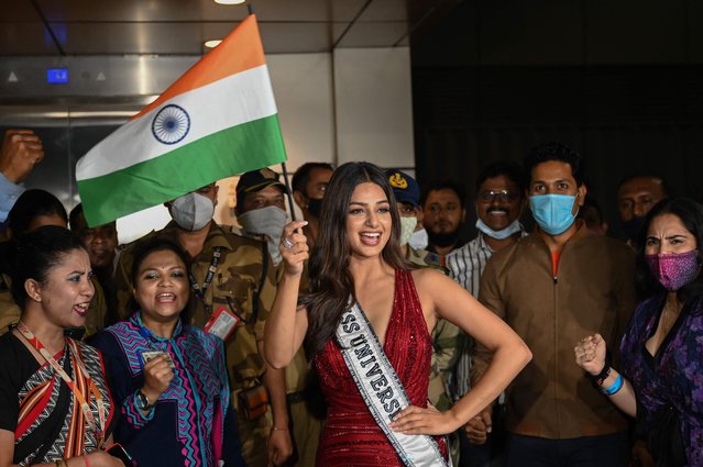 Miss Universe 2021 Harnaaz Sandhu (Miss India), winner of the 70th Miss Universe beauty pageant, waves a national flag as she poses for pictures after arriving at the International airport terminal in Mumbai on December 15, 2021. (Photo by Punit Paranjpe/AFP Photo)