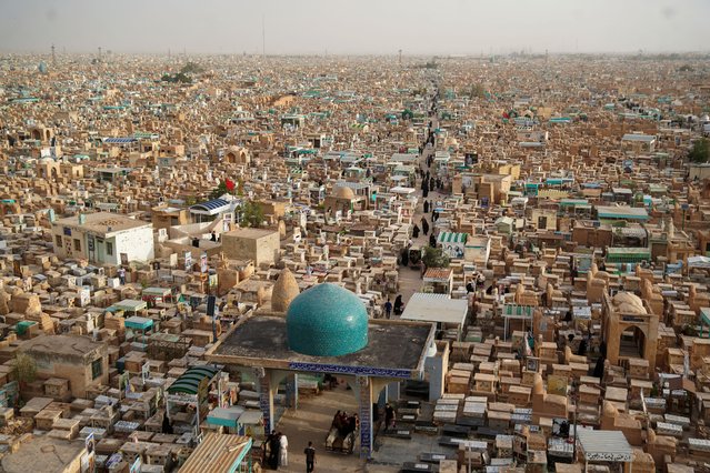 An aerial picture shows Muslim worshippers visiting the graves of relatives at the Wadi-al-Salam cemetery in Iraq's shrine city of Najaf, on the first day of Eid al-Fitr marking the end of the holy fasting month of Ramadan on April 10, 2024. (Photo by Qassem al-Kaabi/AFP Photo)