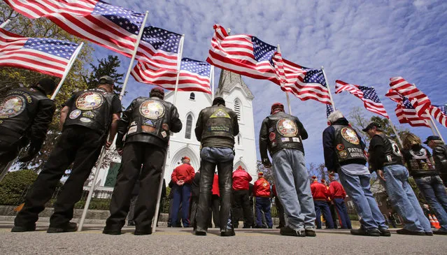 A veteran's motorcycle club stand holding flags flapping in the breeze outside a memorial service for U.S. Marine Cpl. Christopher Orlando outside St. Paul's Catholic Church in Hingham, Mass., Friday, April 29, 2016. Orlando and 11 other Marines died Jan. 14 in a midair collision of two helicopters during a nighttime training mission off Hawaii's coast. (Photo by Charles Krupa/AP Photo)