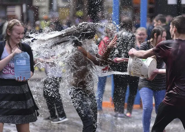 Ukrainians pour water on each other on a street in Lviv, Ukraine, 02 May 2016. The tradition of pouring water was an ancient spring ritual of cleansing on first Monday after Orthodox Easter. (Photo by Mykola Tys/EPA)