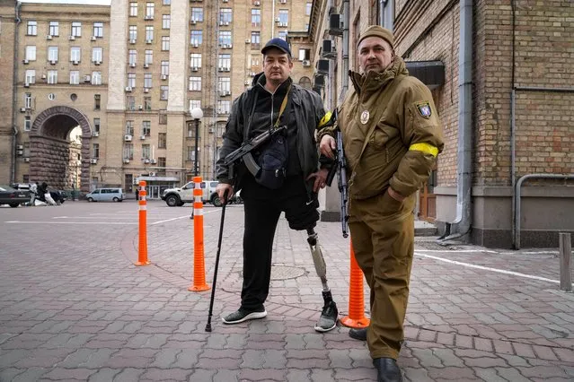 Armed civil defense men pose for a photo while patrolling an empty street due to curfew in Kyiv, Ukraine, Sunday, February 27, 2022. (Photo by Efrem Lukatsky/AP Photo)