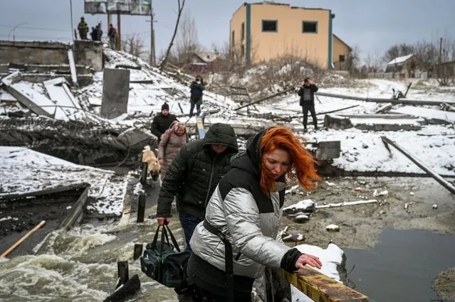 Civilians cross a river on a blown up bridge on Kyiv's northern front on March 1, 2022. Defending capital Kyiv, the “key priority” Ukrainian president said. (Photo by Aris Messinis/AFP Photo)