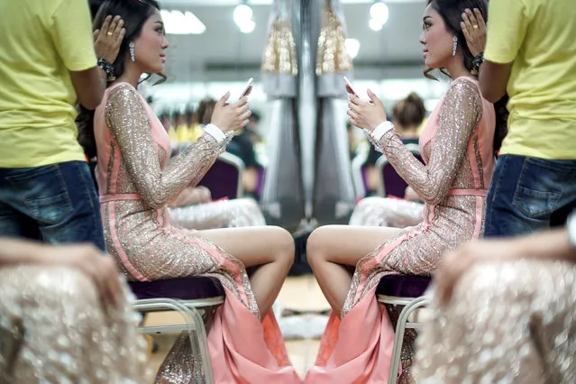 A beauty contestant holds up a mobile phone as she prepares backstage before the final of the annual Miss Tiffany's Universe 2016 transvestite contest in the beach resort town of Pattaya, Thailand, May 13, 2016. (Photo by Athit Perawongmetha/Reuters)