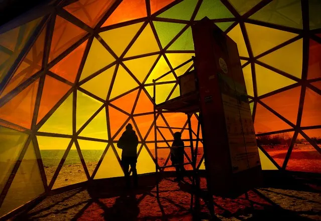 People check out “The Hive”, which is a structural mock up of a beehive, on display at Woodbine Beach on Lake Ontario in Toronto on Monday, February 28, 2022. (Photo by Nathan Denette/The Canadian Press via AP Photo)