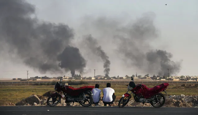 People in Akcakale Sanliurfa province, southeastern Turkey, at the border with Syria, watch smoke billowing inside Syria, during bombardment by Turkish forces, Thursday, October 10, 2019. Turkey's foreign minister says Turkish troops intend to move some 30 kilometers (19 miles) deep into northern Syria and that its operation will last until all “terrorists are neutralized”, a reference to Syrian Kurdish fighters. (Photo by Emrah Gurel/AP Photo)