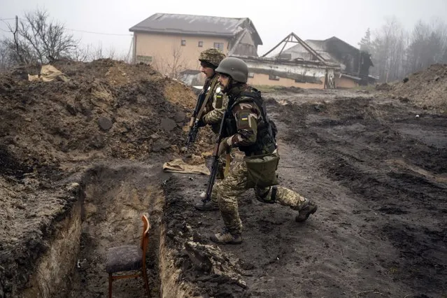 Ukrainian soldiers approach a trench that had been used by Russian soldiers as they retake an area on the outskirts of Kyiv, Ukraine, Friday, April 1, 2022. (Photo by Rodrigo Abd/AP Photo)
