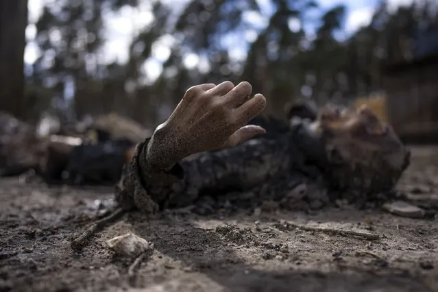 The charred body of a man along with five other people, lie on the ground in Bucha, on the outskirts of Kyiv, Ukraine, Monday, April 4, 2022. (Photo by Rodrigo Abd/AP Photo)