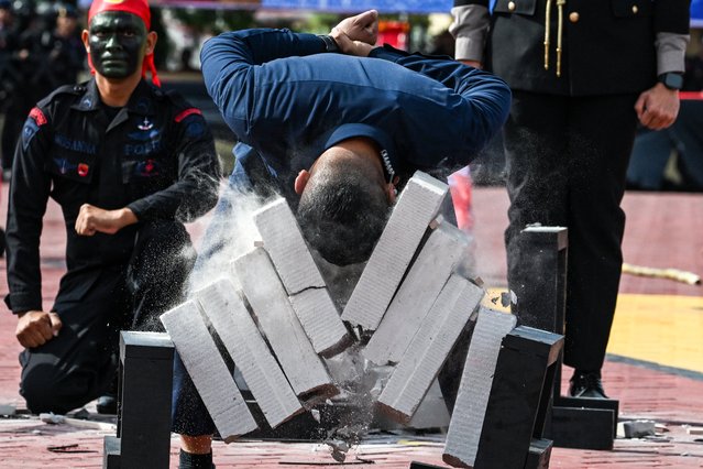 A policeman demonstrates physical strength by breaking blocks of concrete during a ceremony held to commemorate the 78th anniversary of the Indonesian police corps in Banda Aceh on July 1, 2024. (Photo by Chaideer Mahyuddin/AFP Photo)