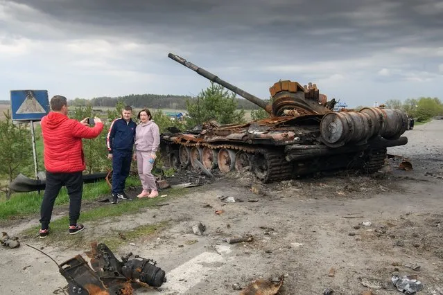 People pose for a picture in front of the debris of Russian military machinery destroyed during Russia's invasion of Ukraine, in the village of Rusaniv, Kyiv region, Ukraine on April 25, 2022. (Photo by Vladyslav Musiienko/Reuters)