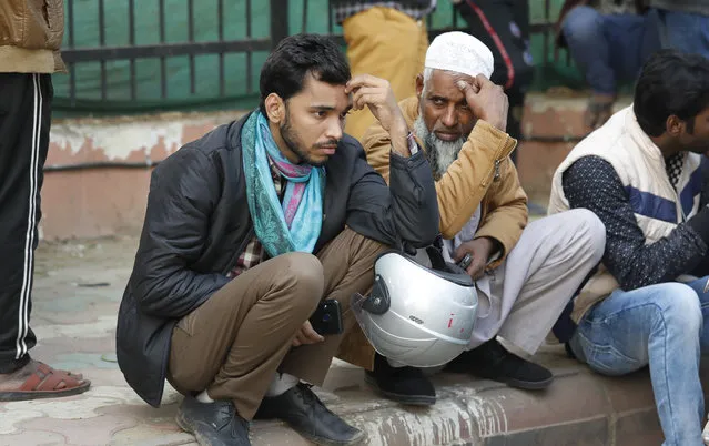 People wait to collect bodies of relatives who died in a fire in New Delhi, India, Sunday, December 8, 2019. Dozens of people died on Sunday in a devastating fire at a building in a crowded grains market area in central New Delhi, police said. (Photo by Manish Swarup/AP Photo)