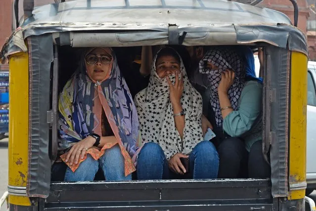 Women cover their faces with cloth while travelling in an autorickshaw on a hot summer day in Amritsar on May 1, 2022. (Photo by Narinder Nanu/AFP Photo)
