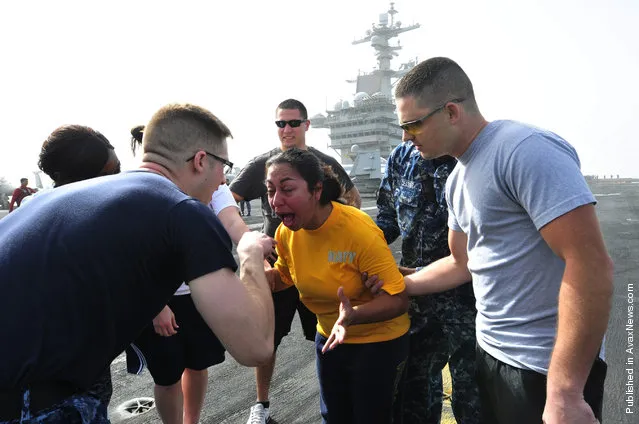 Master-at-Arms 2nd Class Jonathan Prichard instructs Operations Specialist 3rd Class Gladys Jerezrendon, to open her eyes after being sprayed with oleoresin capsicum (OC) spray during a security academy OC spray qualification on the flight deck aboard the Nimitz-class aircraft carrier USS Carl Vinson (CVN 70)