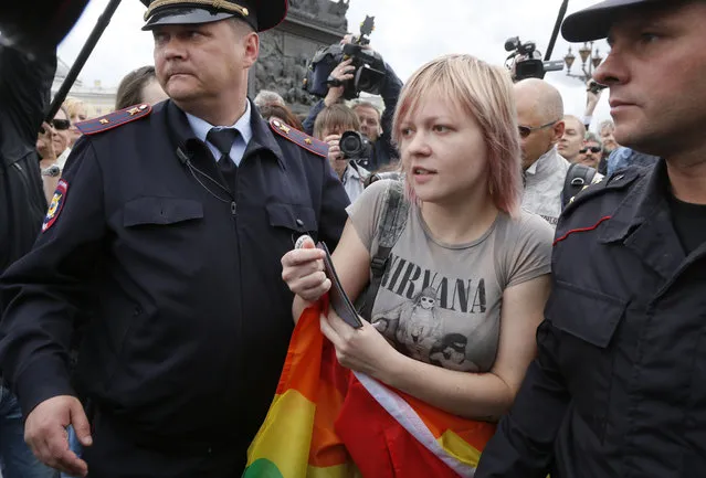 Police officers detain a gay rights activist standing with a rainbow flag during a protest at Dvortsovaya (Palace) Square in St.Petersburg, Russia, Sunday, August 2, 2015. (Photo by Dmitry Lovetsky/AP Photo)